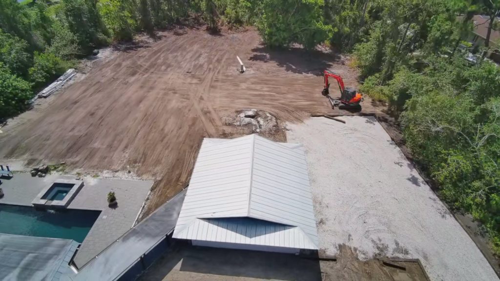 Aerial view of land clearing and site preparation in Bradenton FL with excavator grading residential lot for new construction