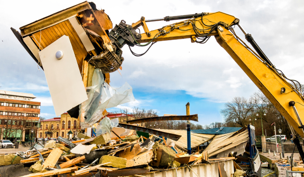 Building demolition contractor in Bradenton using excavator with shear attachment to tear down commercial structure during full-service demolition project