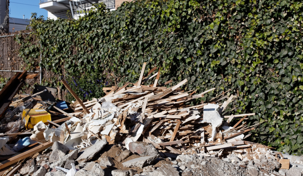 Mixed construction debris pile including wood framing drywall and concrete rubble staged for haul-off during demolition cleanup on an active Parrish FL construction site
